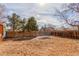 Fenced backyard featuring a mix of trees, dirt, and some snow, creating a serene outdoor space at 6758 W Louisiana Pl, Lakewood, CO 80232