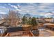 View of the fenced backyard with a wooden deck and shed surrounded by grass, trees, and a cloudy blue sky at 6758 W Louisiana Pl, Lakewood, CO 80232