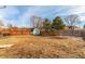 View of the fenced backyard with a wooden deck, shed, and trees under a partially cloudy sky at 6758 W Louisiana Pl, Lakewood, CO 80232