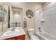 Bright bathroom with tiled shower and tub combination, toilet, vanity, and decorative tree wall art at 8054 E 152Nd Dr, Thornton, CO 80602