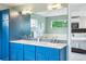 Bathroom with double vanity, blue cabinets, modern lighting, and view to the bedroom at 4220 Quitman St, Denver, CO 80212