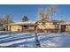 Brick ranch home with a red door and snow-covered yard at 7625 W 23Rd Pl, Lakewood, CO 80214