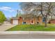 Charming brick home with a lush green lawn, red front door, and inviting blue Adirondack chairs at 4544 W 65Th Ave, Arvada, CO 80003