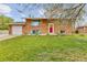 Charming brick home with lush green lawn, bright red door, and inviting blue Adirondack chairs at 4544 W 65Th Ave, Arvada, CO 80003