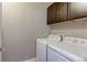 Functional laundry room featuring modern white appliances, dark cabinets, and neutral walls at 13713 Raritan Ln, Broomfield, CO 80023