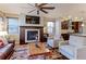 Elegant living room with fireplace, ceiling fan, hardwood floors, and view of the kitchen at 13713 Raritan Ln, Broomfield, CO 80023