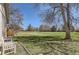 Expansive backyard featuring a lush lawn, mature trees, and a cozy white bench, perfect for outdoor relaxation at 6396 Twin Lakes Rd, Boulder, CO 80301