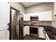 A stainless steel refrigerator, oven, and microwave are featured in this kitchen with white cabinets and dark countertops at 8126 Gray Ct # 499, Arvada, CO 80003