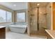 Bright bathroom featuring a soaking tub by the window and glass-enclosed shower with tile surround at 16652 W Archer Ave, Golden, CO 80401