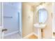 Bathroom with a pedestal sink, round mirror, tiled floors, and a glass-enclosed shower at 16652 W Archer Ave, Golden, CO 80401