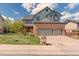 Two story home with brick facade, green siding, a three car garage and a well manicured lawn at 16652 W Archer Ave, Golden, CO 80401