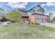 Two-story home with green siding, a brick facade, and lush green lawn and mature landscaping at 16652 W Archer Ave, Golden, CO 80401