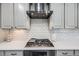 Close up of the kitchen's stainless steel gas range, hood, white countertops, and subway tile backsplash at 7961 E 131St Ave, Thornton, CO 80602