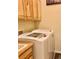 A bright laundry room features a new washer and dryer and wooden cabinetry at 6656 S Shawnee St, Aurora, CO 80016