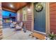 Cozy front porch with chairs, lanterns, and a teal front door with a floral wreath at 10104 Nadine Ave, Parker, CO 80134