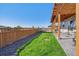 Large backyard with covered patio, fenced perimeter, and grassy area at 803 William Way, Brighton, CO 80603