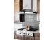 Close up of a range hood above a six-burner gas cooktop surrounded by dark stained cabinets at 16791 W 48Th Ln, Golden, CO 80403