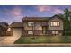 Charming two-story home with a brick and siding exterior and well-maintained front yard at dusk at 1549 Dean Dr, Northglenn, CO 80233