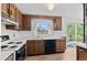 A kitchen with wood cabinets, white appliances, and a view from the window at 1549 Dean Dr, Northglenn, CO 80233