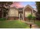 Charming brick home with manicured lawn and beautiful bay window, set against a colorful sunset sky at 1011 S Valentia St # 3, Denver, CO 80247
