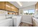 Bright laundry room featuring wooden cabinets, modern appliances, and a window with a view at 4879 S Johnson St, Littleton, CO 80123