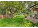 Expansive backyard featuring a lush lawn, mature trees, and a comfortable patio with outdoor seating at 6128 S Coventry E Ln, Littleton, CO 80123
