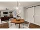Bright dining area with hardwood floors next to the living room and featuring a modern pendant light and sliding barn door at 6128 S Coventry E Ln, Littleton, CO 80123