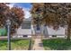 Charming home with white siding and a well-manicured lawn, framed by vibrant, mature trees. A welcoming entrance at 2845 Eaton St, Wheat Ridge, CO 80214