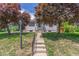 Charming home with white siding and a well-manicured lawn, framed by vibrant, mature trees. A welcoming entrance at 2845 Eaton St, Wheat Ridge, CO 80214