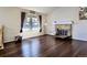 Open living room boasting hardwood floors, a brick fireplace, and a large window for plenty of light at 12425 Bellaire Dr, Thornton, CO 80241
