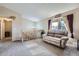 Bright living room with a plush sofa, large window, and staircase leading to upper level at 12425 Bellaire Dr, Thornton, CO 80241