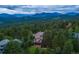 Aerial view of a luxury home with a deck surrounded by evergreen trees, with a mountain backdrop at 1952 Columbine Ct, Golden, CO 80401