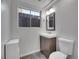 Bathroom showcasing a wood vanity, sink, toilet, mirror, slate floors, and a window at 8047 Lee Ct, Arvada, CO 80005