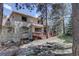 View of the back of the house with mature trees, natural stone landscaping, and patio area at 2828 Keystone Dr, Evergreen, CO 80439