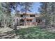 Back of the house with large windows, a patio, a tile roof, and a spacious backyard with mature trees at 2828 Keystone Dr, Evergreen, CO 80439