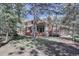 View of the back of the house with a well-maintained lawn, mature trees, and outdoor deck space at 2828 Keystone Dr, Evergreen, CO 80439