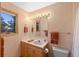 Bathroom featuring a wood vanity with a sink, a medicine cabinet, and decorative wallpaper at 2828 Keystone Dr, Evergreen, CO 80439