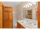 Cozy bathroom featuring neutral tile, wood vanity, and framed mirror at 2828 Keystone Dr, Evergreen, CO 80439