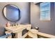 Stylish powder room with blue walls, a pedestal sink, and a round mirror at 6401 S Millbrook Way, Aurora, CO 80016