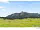 Picturesque view of the Flatirons mountains under a blue sky with green field and open grass at 911 Lincoln Pl, Boulder, CO 80302