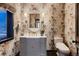 Charming powder room with patterned wallpaper, gray vanity and designer mirror at 6483 S Prince St, Littleton, CO 80120