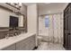 Modern bathroom featuring gray vanity with dual sinks and stylish shower with floral curtain at 6483 S Prince St, Littleton, CO 80120