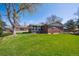 Backyard featuring green grass, a red brick sunroom, and shade trees at 11609 Fowler Dr, Northglenn, CO 80233