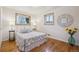 This bedroom features two windows, hardwood floors, and a bed with black side tables at 11609 Fowler Dr, Northglenn, CO 80233