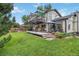 Exterior home view from the backyard featuring a deck, patio, green grass, and mature trees at 3709 S Fairplay Way, Aurora, CO 80014