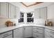 Well-lit kitchen with white cabinetry, updated appliances, and a charming view from the windows at 7040 Routt St, Arvada, CO 80004