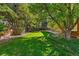 Lush backyard featuring a well-manicured lawn, mature trees, and a privacy fence at 7548 S Crocker Ct, Littleton, CO 80120
