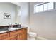 Bathroom features wood cabinet, dark granite countertop, white sink and toilet, and small window at 365 Casalon Pl, Superior, CO 80027