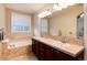 Bathroom features double sinks, tile backsplash, large mirror, and soaking tub at 10100 Bluffmont Ln, Lone Tree, CO 80124