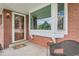 Inviting front porch with brick facade and a stylish glass door, complemented by a cozy chair and decor at 11754 W 28Th Ave, Lakewood, CO 80215